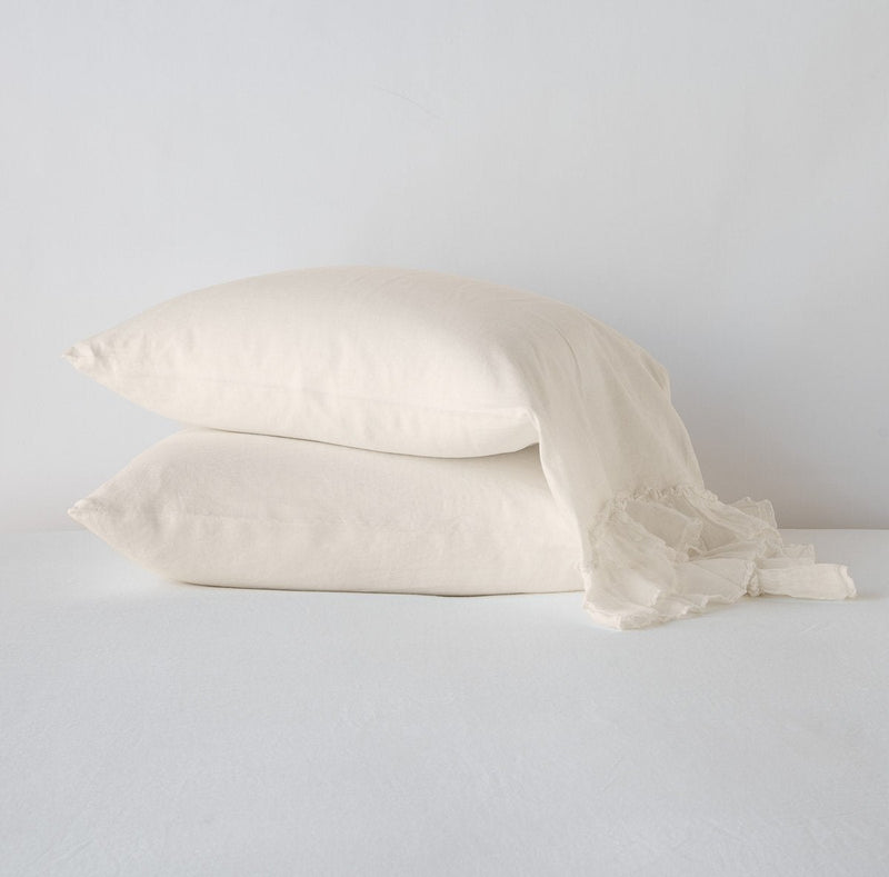 Linen Whisper Pillowcase (Single) | Parchment | Two sleeping pillows stacked at a slight angle against a plain background, showcasing ruffle trim detail - side view.