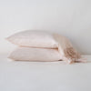 Linen Whisper Pillowcase (Single) | Pearl | Two sleeping pillows stacked at a slight angle against a plain background, showcasing ruffle trim detail - side view.