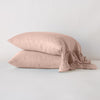 Linen Whisper Pillowcase (Single) | Rouge | Two sleeping pillows stacked at a slight angle against a plain background, showcasing ruffle trim detail - side view.