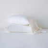 Linen Whisper Pillowcase (Single) | White | Two sleeping pillows stacked at a slight angle against a plain background, showcasing ruffle trim detail - side view.