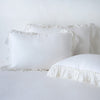 Linen Whisper Sham | White | two shams leaning upright and one laying flat at an angle in the foreground, against a blank background.