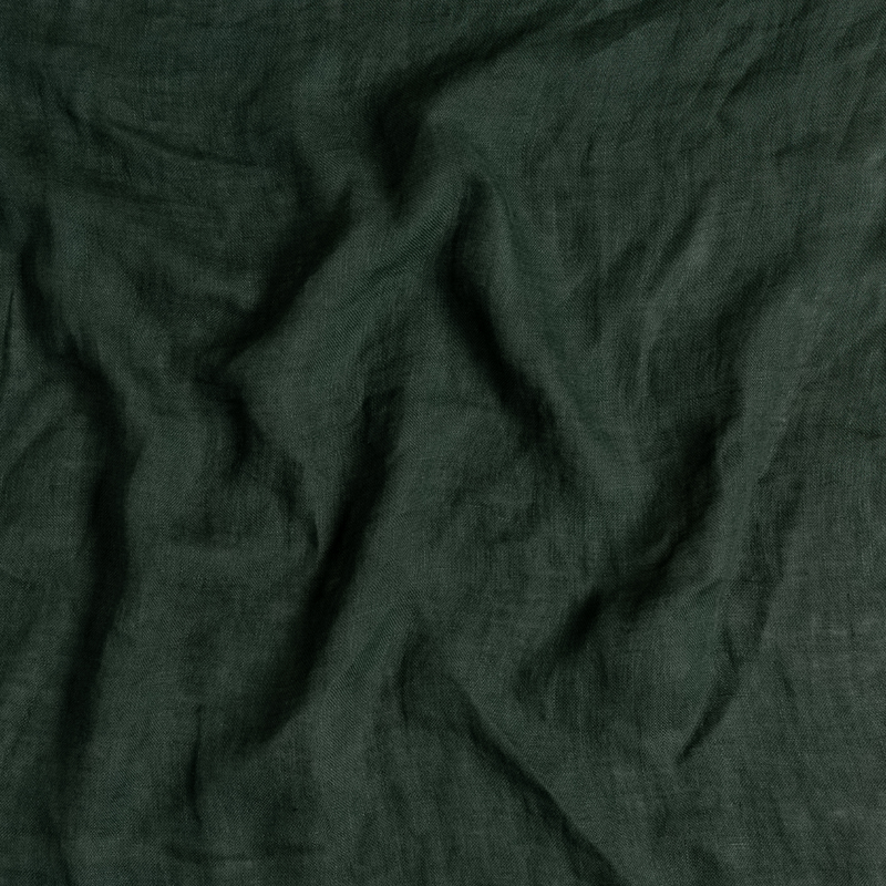 Linen Whisper Crib Skirt | Juniper | A close up of linen whisper fabric in Juniper, a deep green tone.