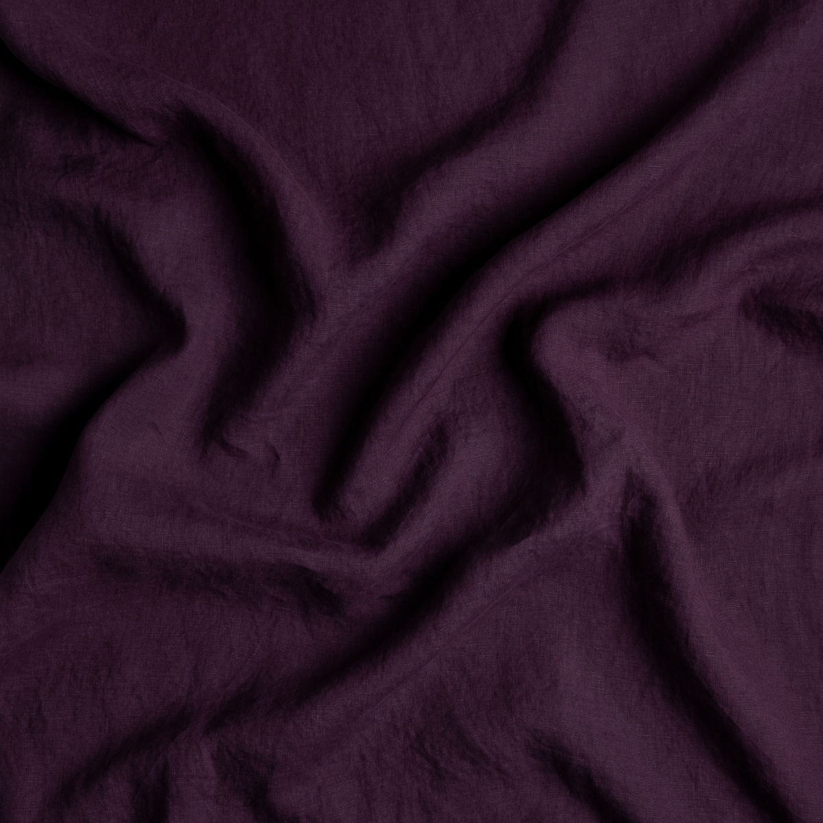 Linen Crib Skirt | Fig | A close up of linen fabric in fig, a richly saturated purple-garnet.