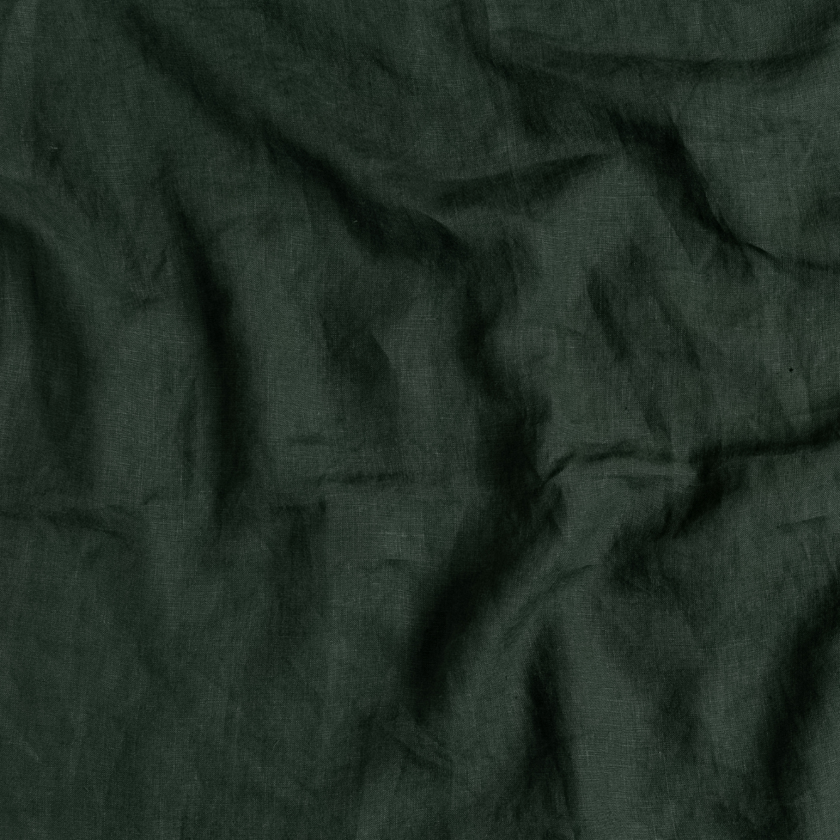 Linen Bed Skirt | Juniper | A close up of linen fabric in Juniper, a deep green tone.