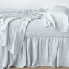 Linen bed skirt in cloud, with matching rumpled sheets and sleeping pillows - side view.