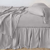 Linen Bed Skirt | Fog | bed skirt with matching rumpled sheets and sleeping pillows - side view.