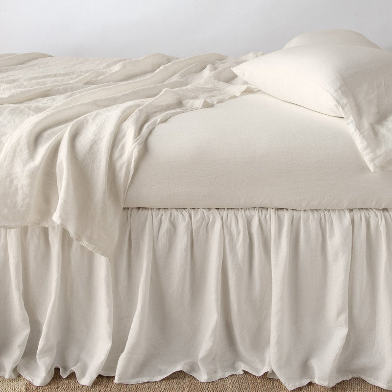 Linen Bed Skirt | Parchment | bed skirt with matching rumpled sheets and sleeping pillows - side view.