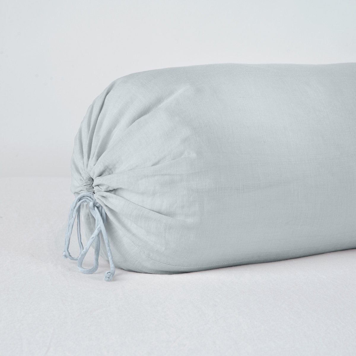 Linen Throw Pillow | Cloud | Close-up bolster end detail, angled view to show gathered closure and satin ties.