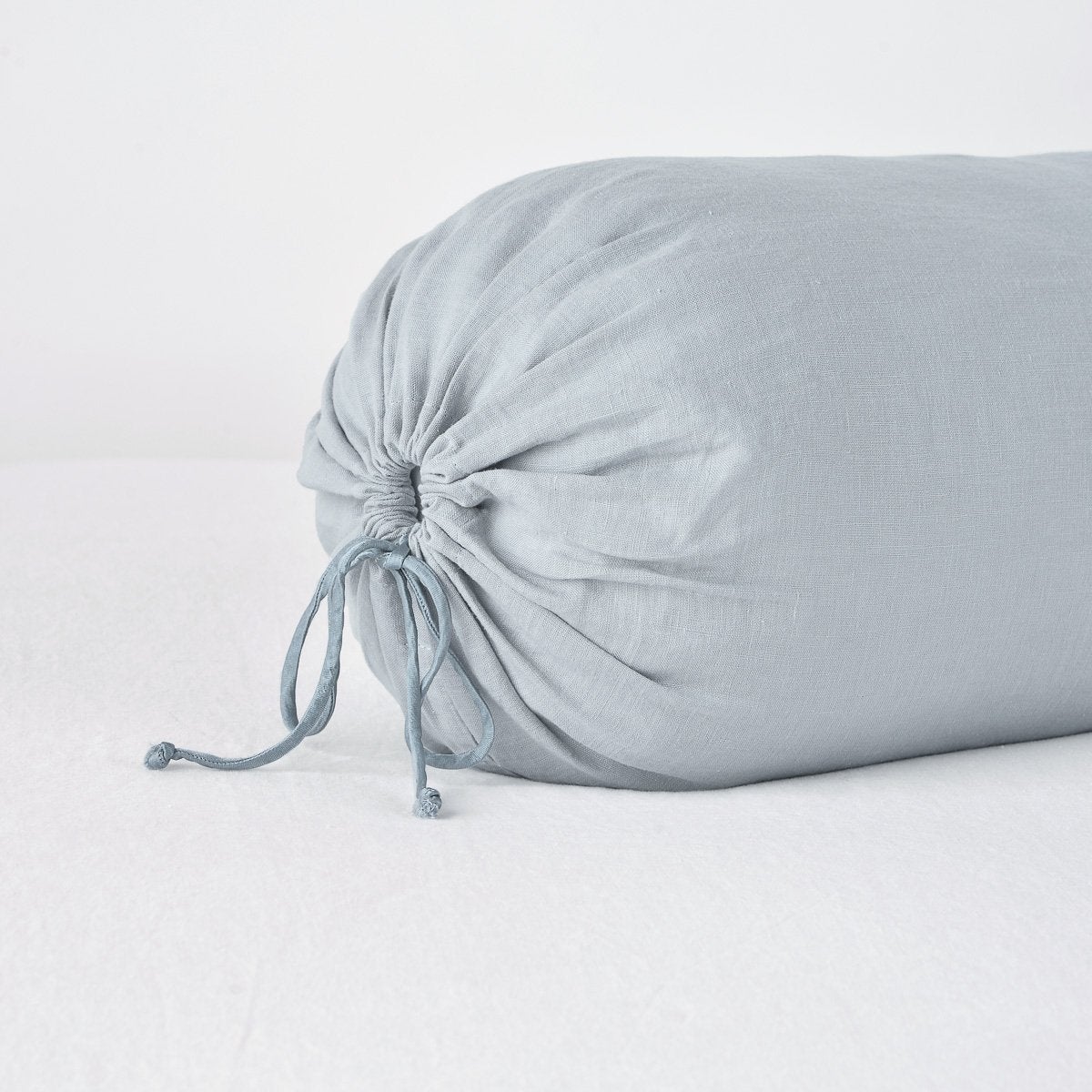 Linen Throw Pillow | Mineral | Close-up of Linen bolster end detail in mineral, angled to show gathering and satin ties.