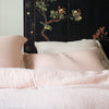 Linen duvet cover and shams in soft pearl pink with dramatic dark floral wall panel - cropped head-on view.