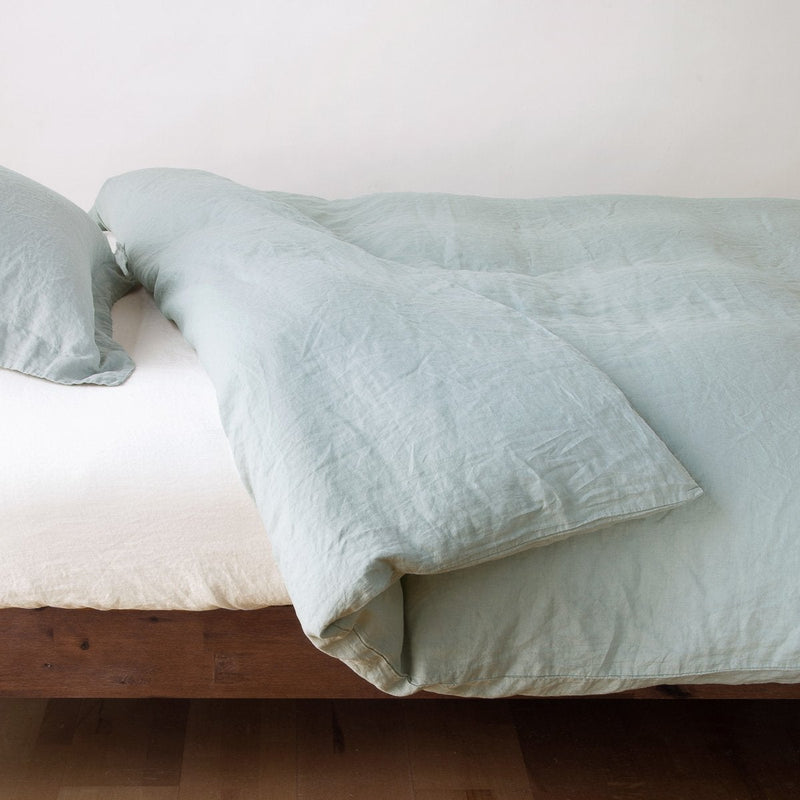 Linen Duvet Cover | Eucalyptus | duvet cover neatly folded back over white linen sheeting - side view.