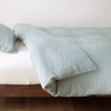 Linen Twin Duvet Cover | Eucalyptus | duvet cover neatly folded back over white linen sheeting - side view.