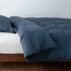 Linen Twin Duvet Cover | Midnight | duvet cover neatly folded back over white linen sheeting - side view.