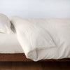 Linen Twin Duvet Cover | Parchment | duvet cover neatly folded back over matching linen sheeting - side view.