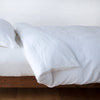 Linen Twin Duvet Cover | White | duvet cover neatly folded back over white linen sheeting - side view.