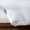 Linen Twin Duvet Cover | Winter White | duvet cover neatly folded back over white linen sheeting - side view.