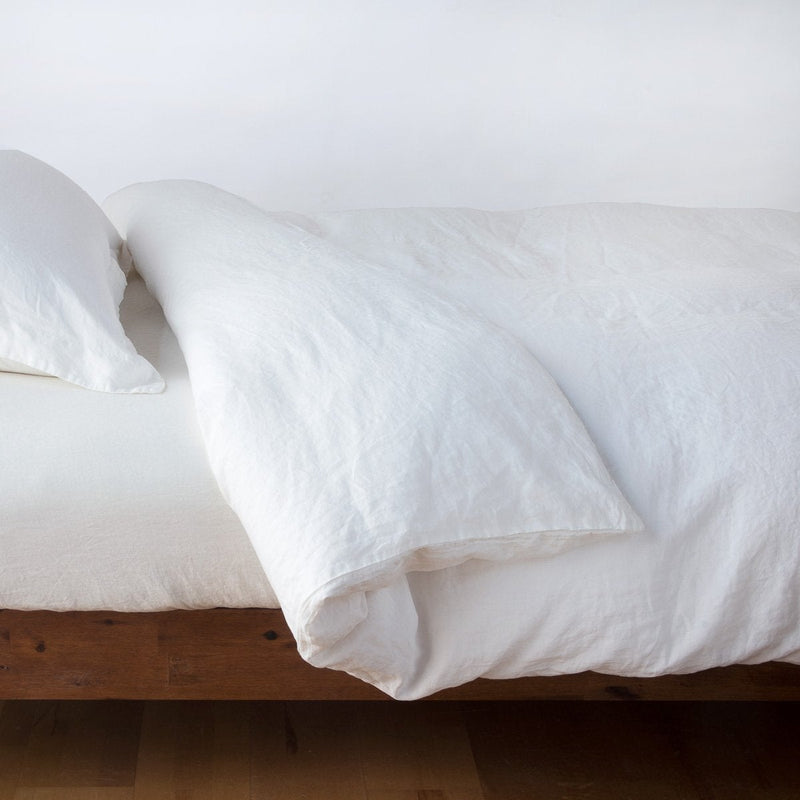 Linen Twin Duvet Cover | Winter White | duvet cover neatly folded back over white linen sheeting - side view.
