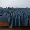 Linen Twin Fitted Sheets | Midnight | fitted sheet with matching rumpled flat sheet and sleeping pillow - side view.
