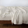 Linen Fitted Sheet | Parchment | fitted sheet with matching rumpled flat sheet and sleeping pillow - side view.