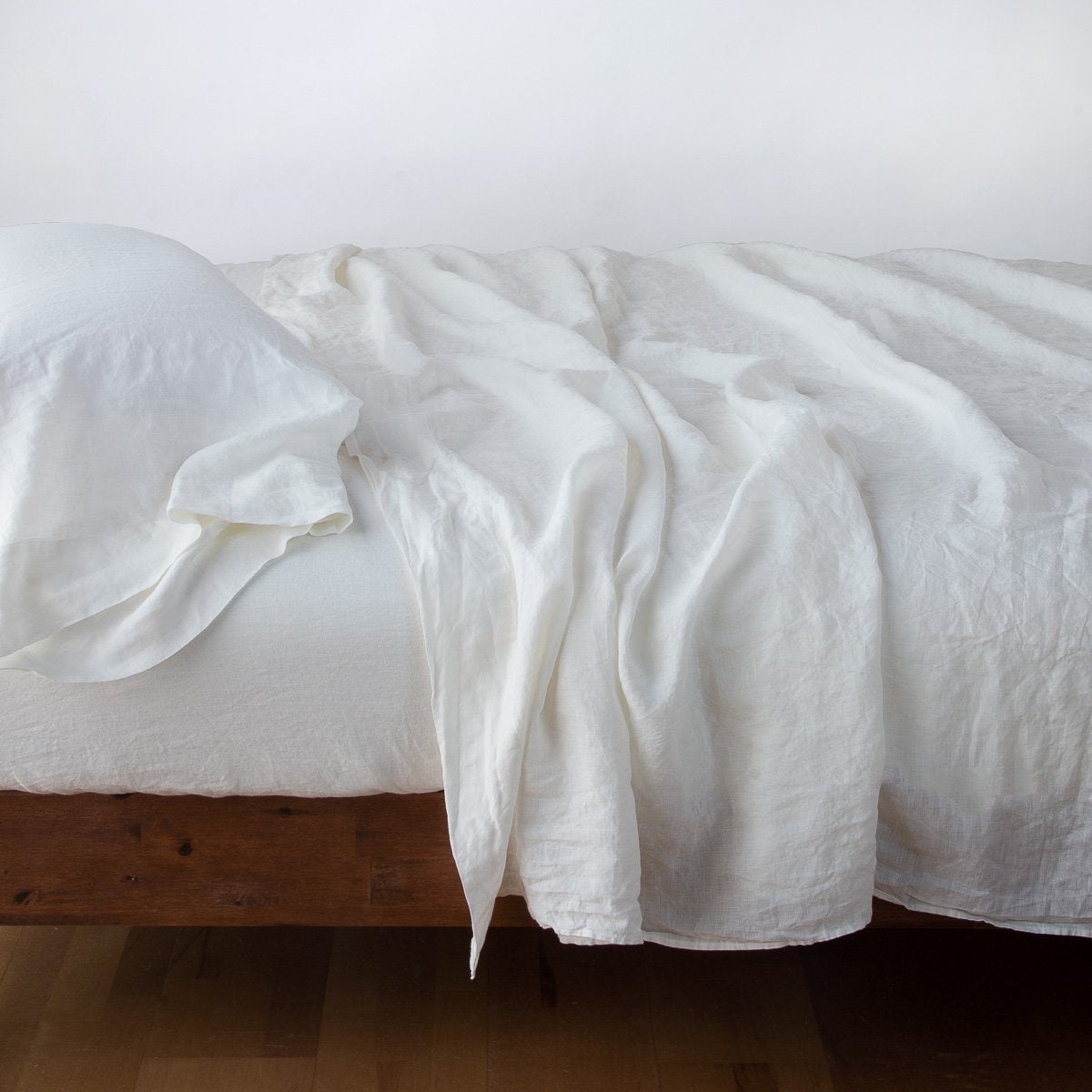 Winter White | Linen fitted sheet in winter white, with matching rumpled flat sheet and sleeping pillow - side view.