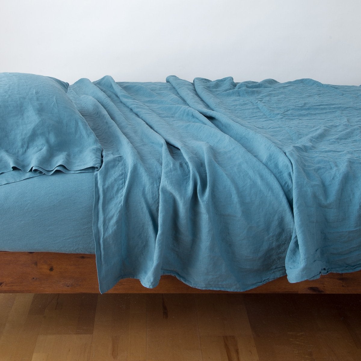 Linen Twin Flat Sheet | Cenote | Rumpled linen sheeting with matching sleeping pillow - side view.