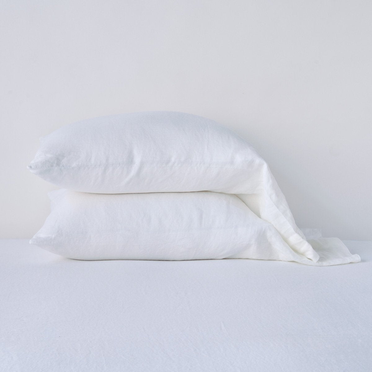 Linen Standard Pillowcase (Single) | White | Two sleeping pillows neatly stacked against a white background - side view.