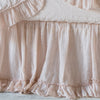 Linen Whisper Crib Skirt | Pearl | Close-up of crib skirt, lightly puddled on distressed wood floor, showcasing ruffle detail.