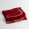 Loulah Baby Blanket | Poppy | an overhead shot of a folded silk velvet baby blanket with a raw-edged eyelash ruffle detail.