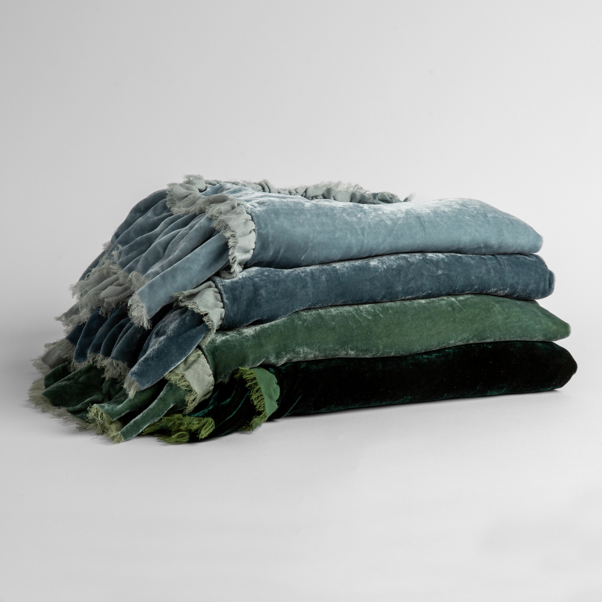 Loulah Baby Blanket | a stack of four silk velvet blankets in cloud, mineral, eucalyptus and jade.