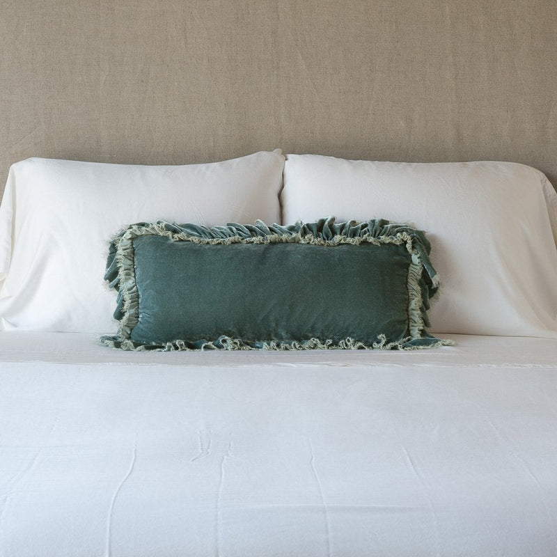 Loulah Throw Pillow | Eucalyptus | pillow on a white bed - cropped end of bed view.