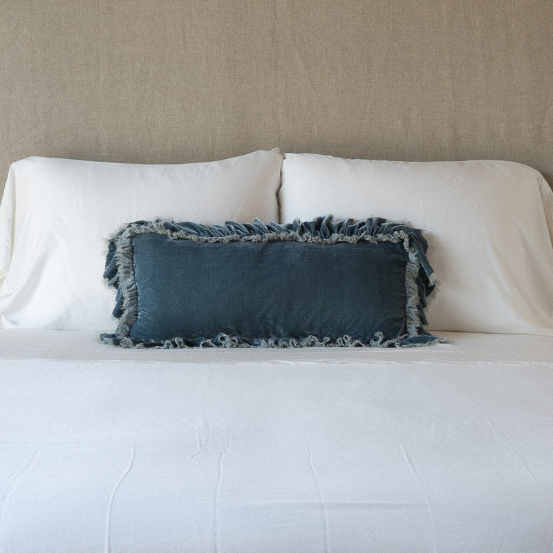 Loulah Throw Pillow | Mineral | pillow on a white bed - cropped end of bed view.