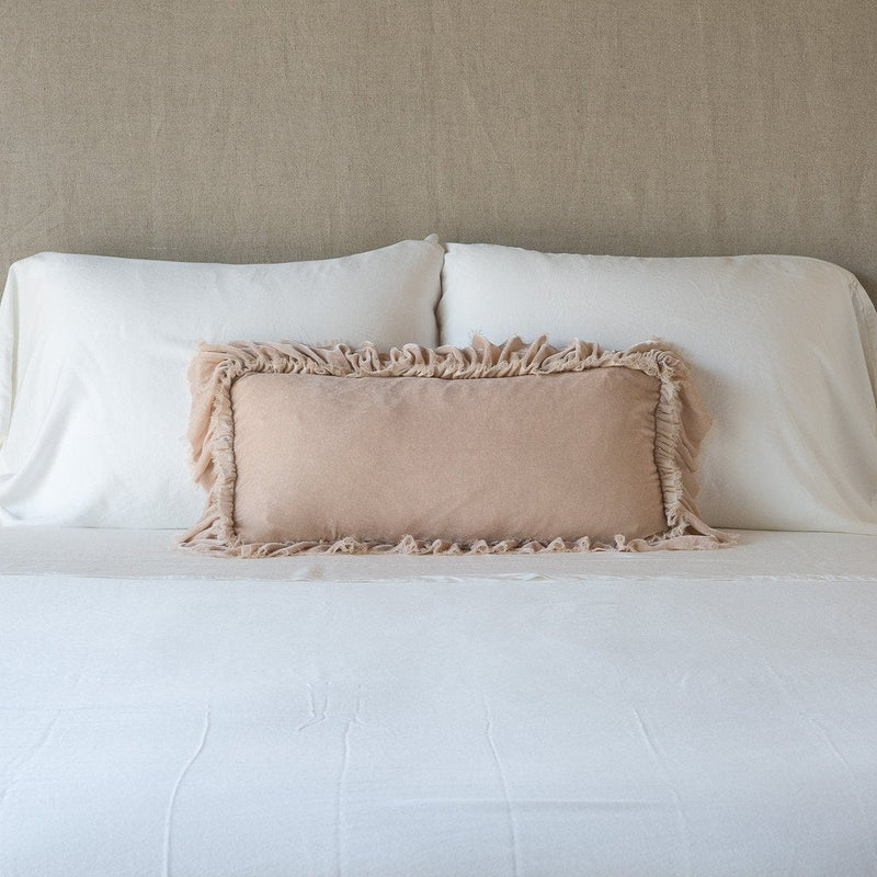 Loulah Throw Pillow | Pearl | pillow on a white bed - cropped end of bed view.