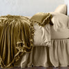 Loulah Blanket | Honeycomb | throw blanket draped over a monochromatic bed, shown with matching throw pillow - side view.