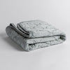 Luna Baby Blanket | Cloud | quilted charmeuse blanket folded and shown against a white background from a slight overhead angle.