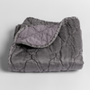 Luna Baby Blanket | French Lavender | quilted charmeuse blanket folded with a corner folded back to show the contrast of the linen back - shown slightly overhead against a white background.