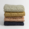 Luna Baby Blanket | A stack of four quilted silk charmeuse baby blankets shown straight on against a white background. Blankets shown in Fog, Honeycomb, Rouge and Midnight