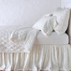 Luna Coverlet | Winter White | coverlet neatly folded back to reveal linen reverse, on a monochromatic bed - side view.