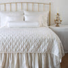Luna Twin Coverlet | Winter White | Luna coverlet on a shining, monochromatic bed with matching shams and charmeuse pillows and bed skirt - winter white, end of bed view.