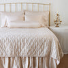 Luna Sham | Pearl | shams on a shining, monochromatic bed with matching coverlet - end of bed view.
