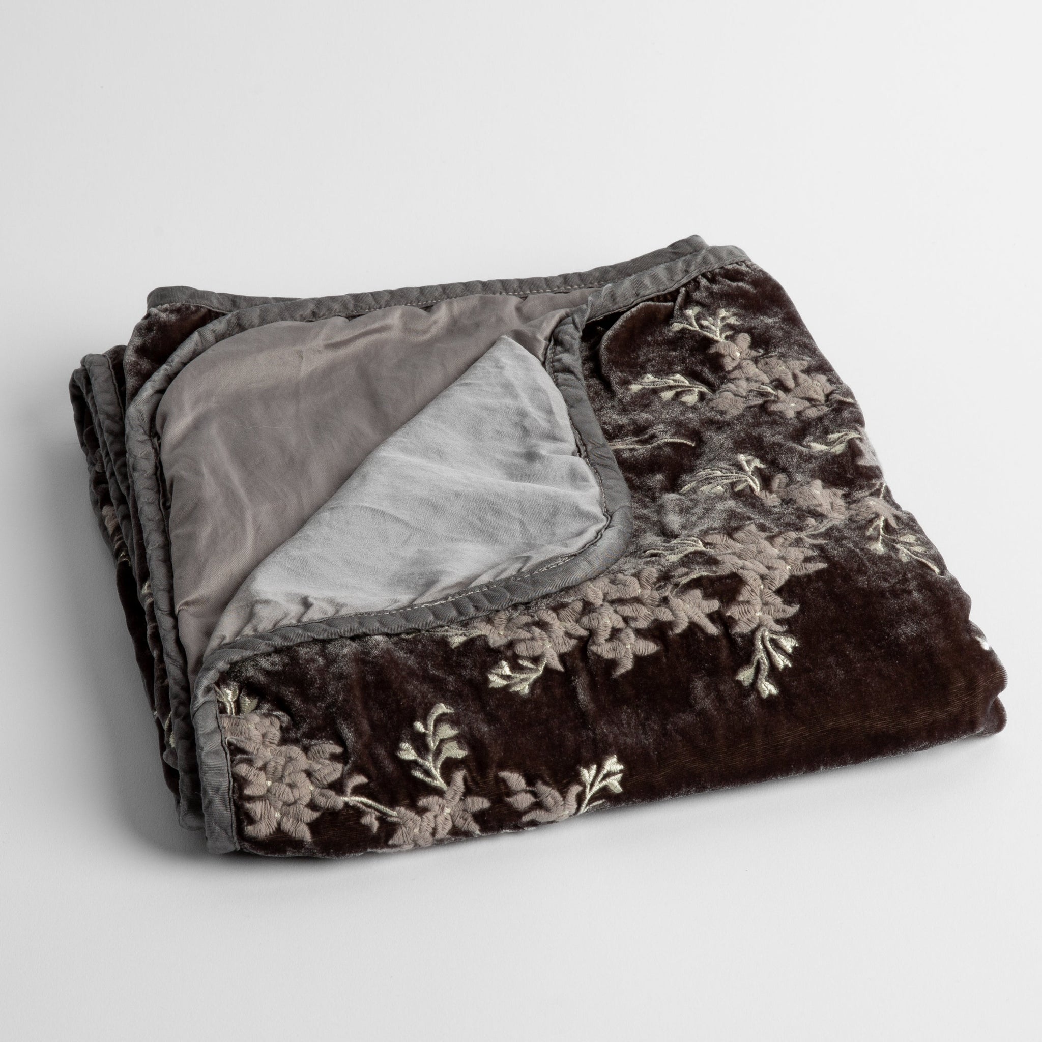 Lynette Baby Blanket | Moonlight | embroidered silk velvet baby blanket folded with a corner folded back to show the trim and back of the blanket - shot overhead at a slight angle against a white background.