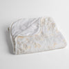 Lynette Baby Blanket | White | embroidered silk velvet baby blanket folded with a corner folded back to show the trim and back of the blanket - shot overhead at a slight angle against a white background.