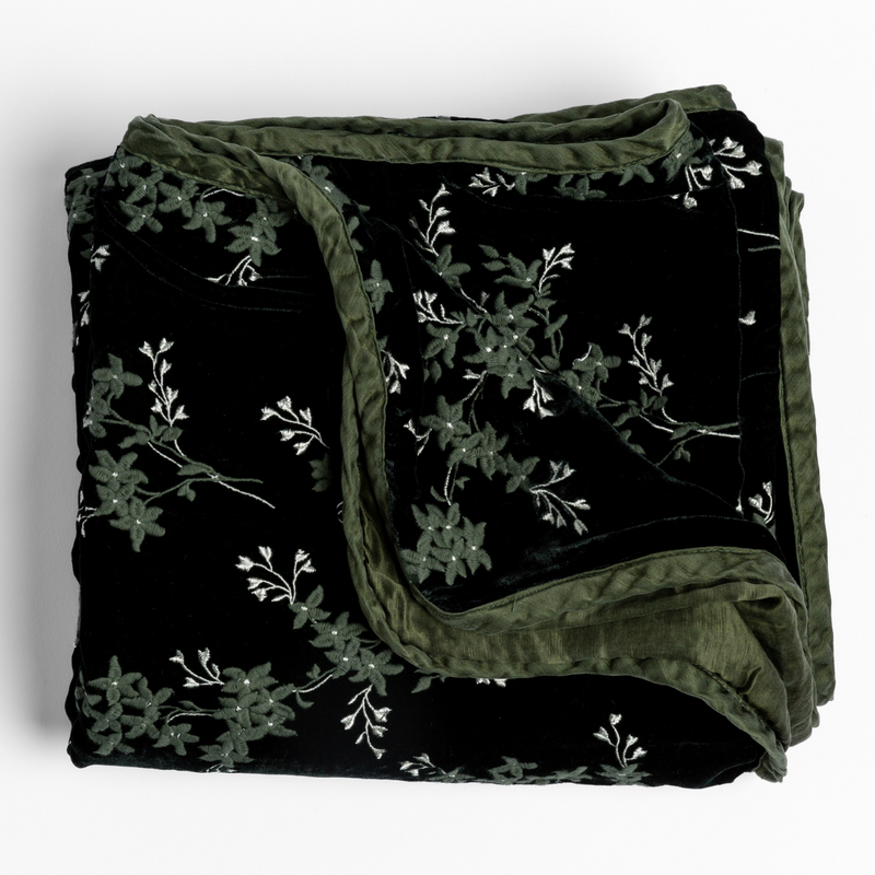 Lynette Blanket | Juniper | embroidered silk velvet blanket folded with its corners folded back showing the trim contrast - overhead and against a white background.