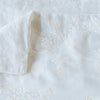 Lynette Blanket | White | Close up of blanket, with a corner turned back to showcase the linen back - overhead view.