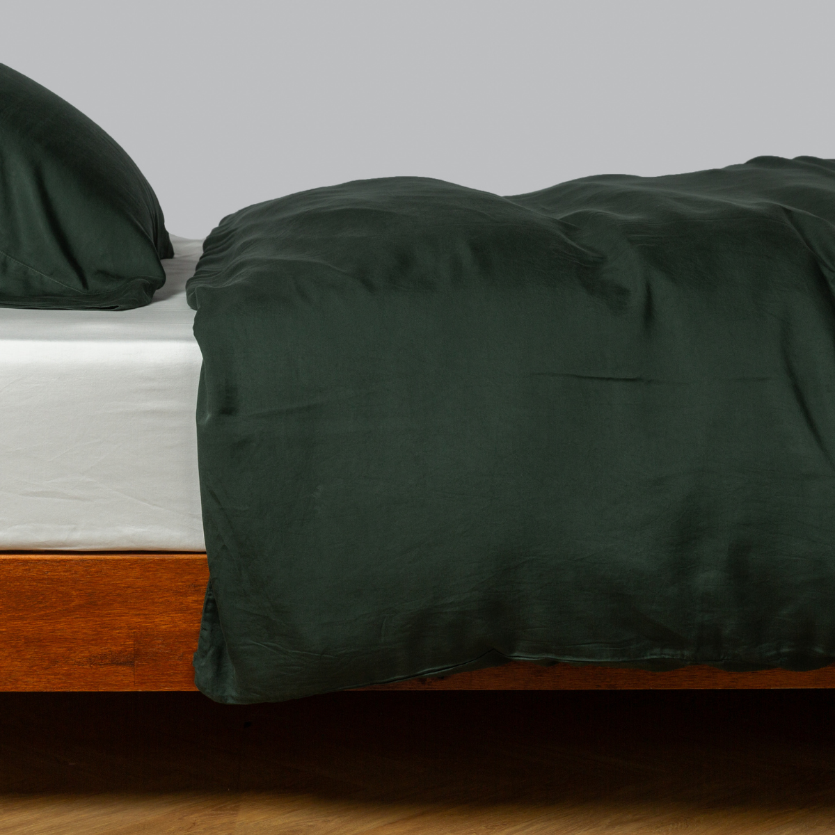 Madera Luxe Duvet Cover | Juniper | tencel™ duvet cover with matching sleeping pillow from the madera luxe collection on a bed dressed with a winter white fitted sheet - side view.