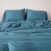 Madera Luxe duvet cover with matching sleeping pillows and sheeting against a white background - cenote, end of bed view.