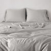 Madera Luxe Twin Duvet Cover | Fog | duvet cover with matching sleeping pillows and sheeting against a white wall - end of bed view.