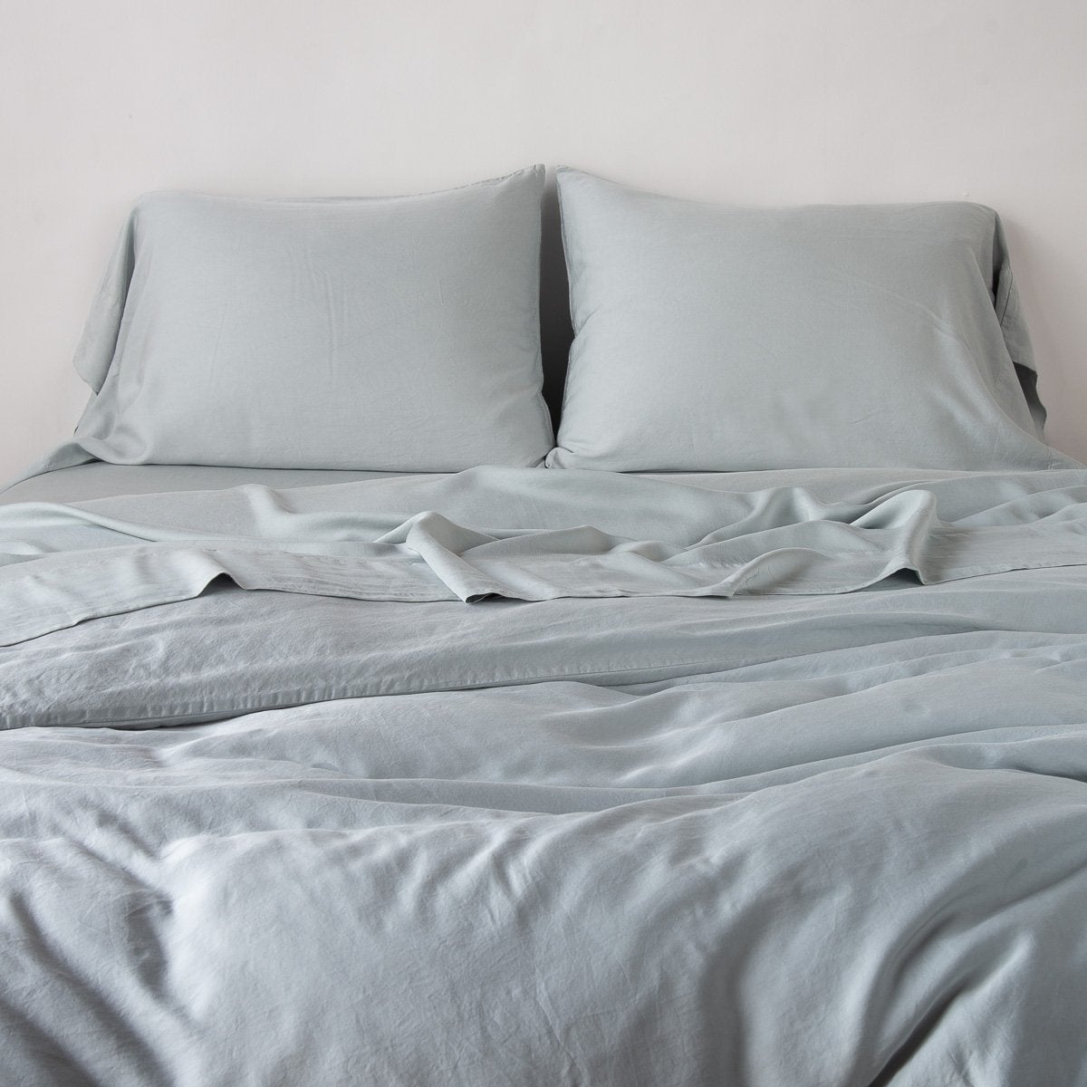Madera Luxe Duvet Cover | Mineral | duvet cover with matching sleeping pillows and sheeting against a white wall - end of bed view.