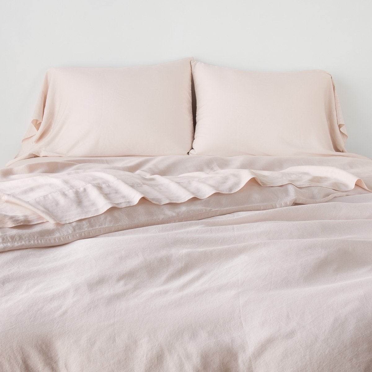 Madera Luxe Duvet Cover | Pearl | duvet cover with matching sleeping pillows and sheeting against a white wall - end of bed view.