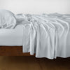 Madera Luxe Fitted Sheet | Cloud | fitted sheet with matching rumpled flat sheet and sleeping pillow - side view.