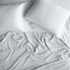 Madera Luxe Fitted Sheet | Cloud | rumpled sheeting and sleeping pillows - overhead view.